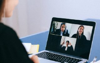 Woman using laptop for a conference call, three other women are displayed on screen