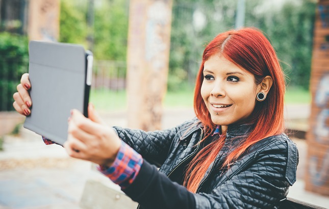 Hispanic female with redhair holds a laptop
